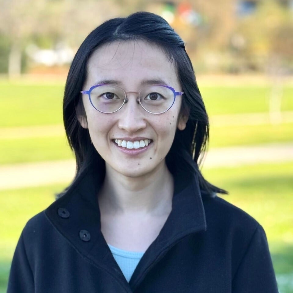 A headshot of a woman with dark har and glasses