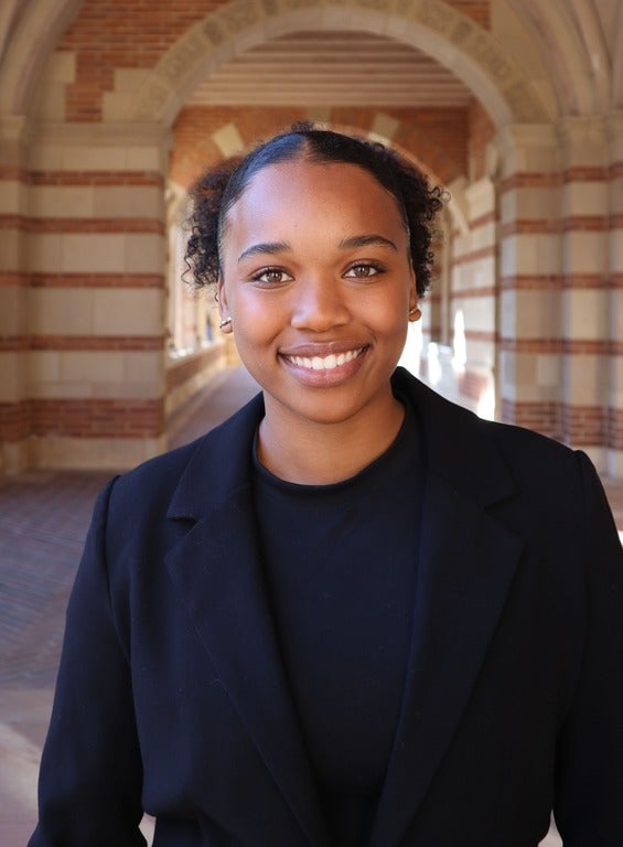 A young woman in a suit jacket standing at Royce Hall