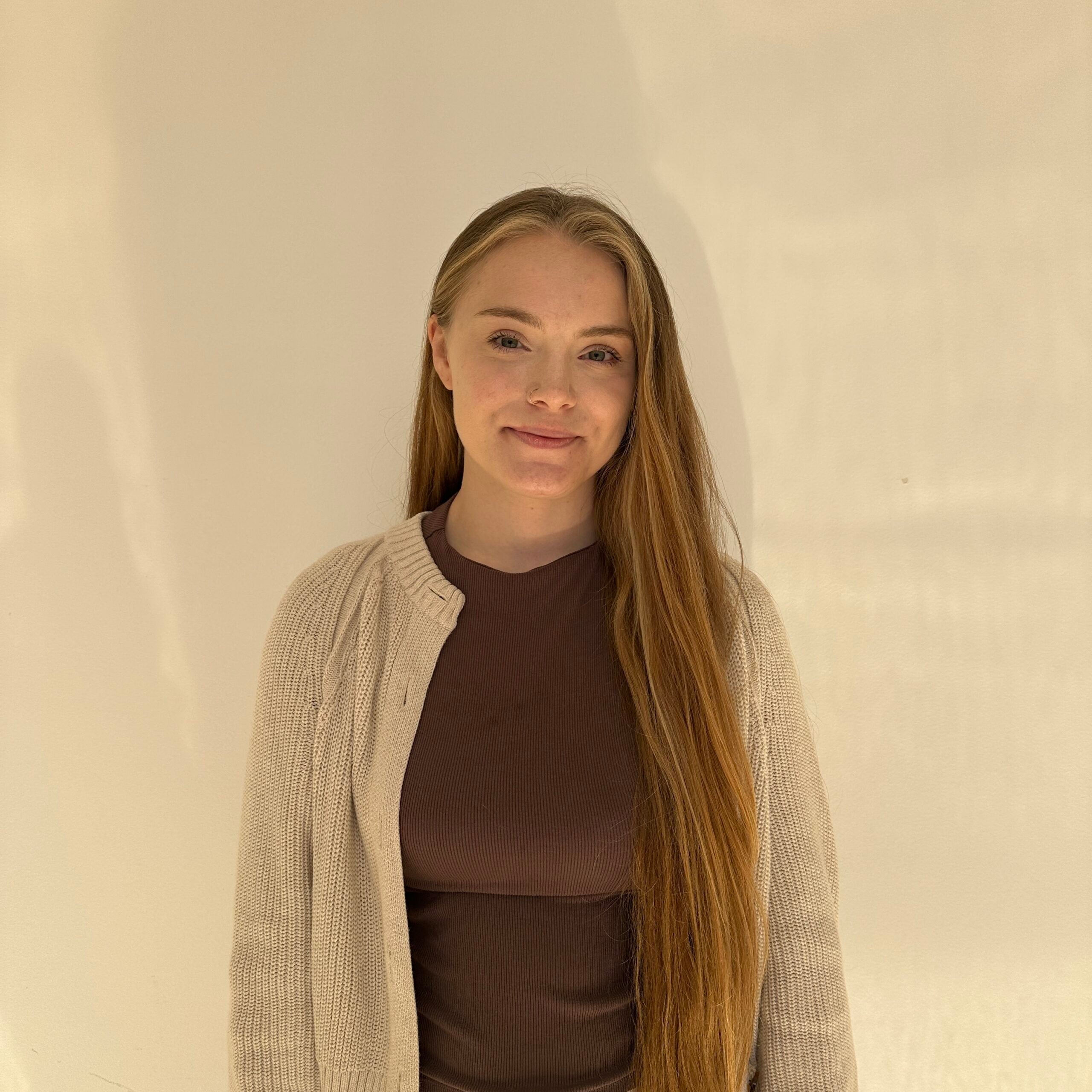 A woman with blond hair wearing a brown shirt and a cardigan
